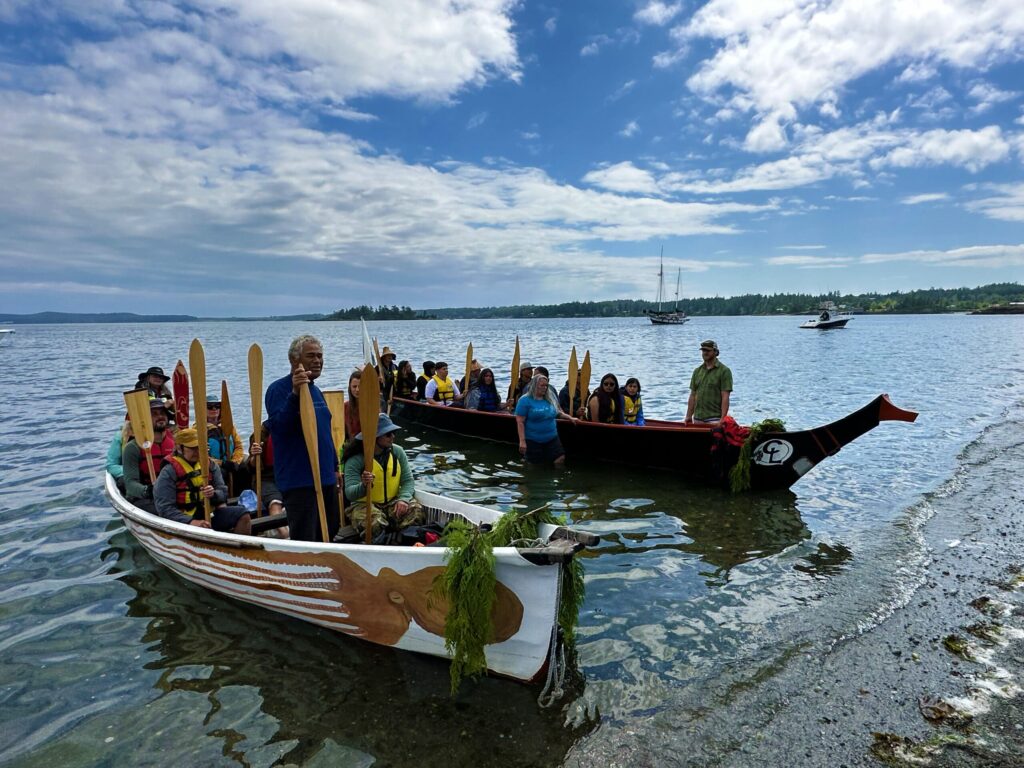 two canoes with people inside docked on the shore in a gathering of the Eagles.