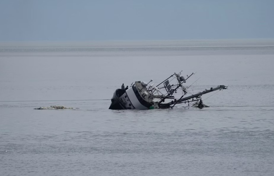A fishing vessel (the Aleutian Isle) sinks near San Juan Island. Crew members stand on the starboard side of the vessel as it sinks.